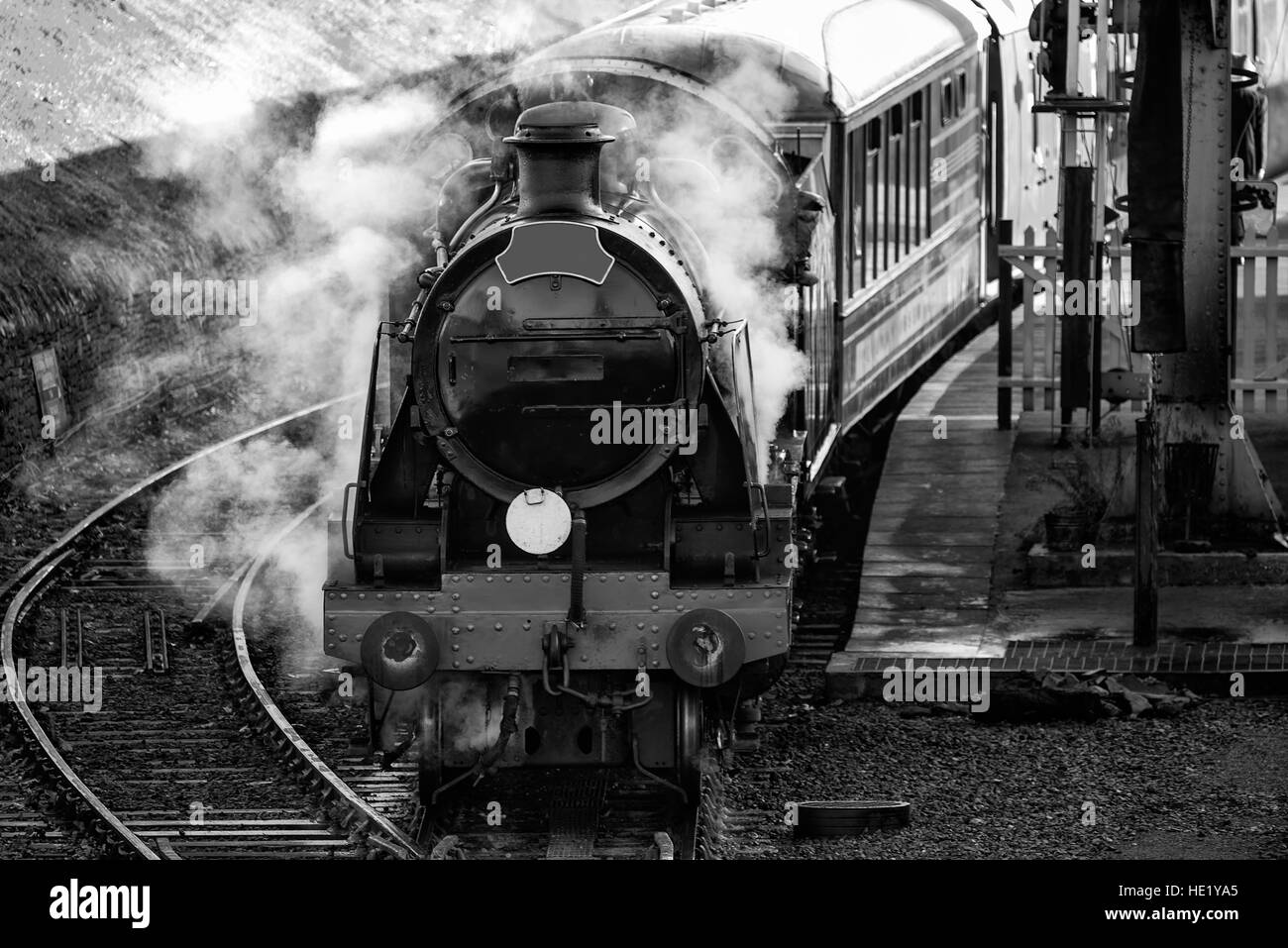 Historische Oldtimer Eisenbahn Dampfmaschine in der Station mit Volldampf schnaufend in schwarz / weiß Stockfoto