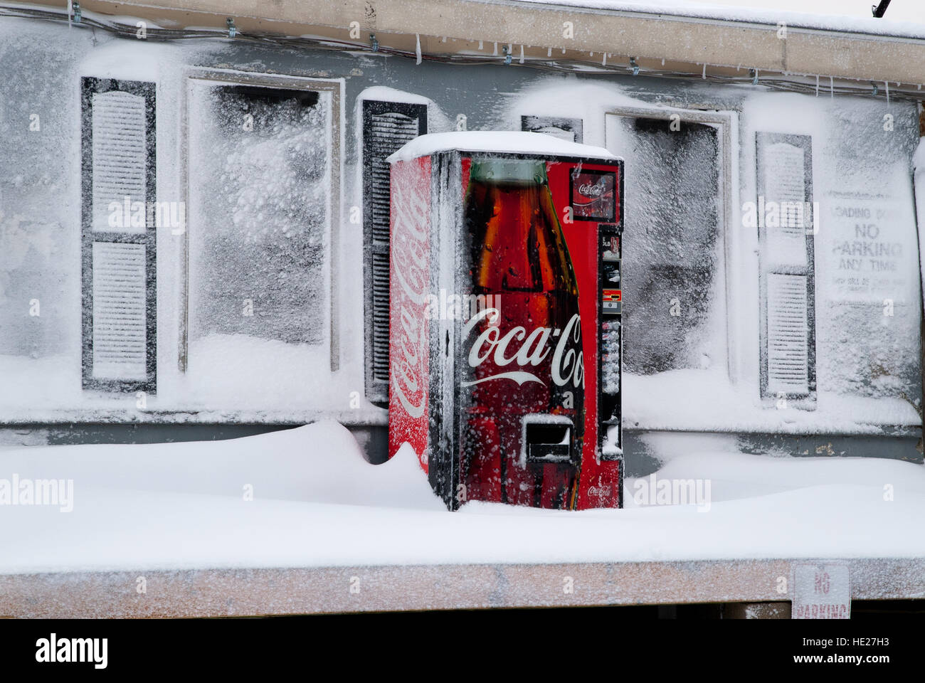 Eine Coca-Cola-Maschine steht trotzig auf einer externen Plattform Blizzard schneebedeckt. Stockfoto