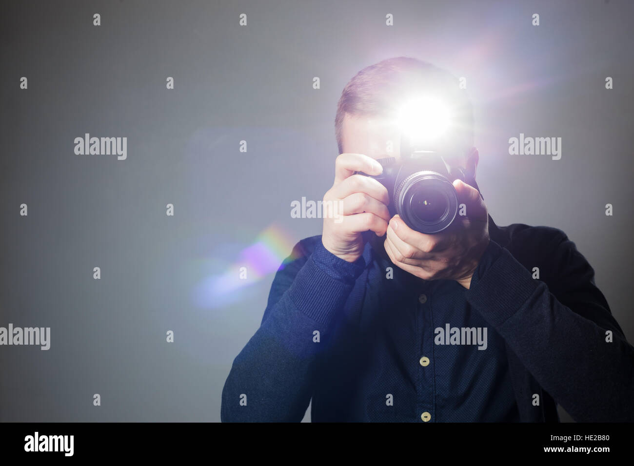 Junger Mann nimmt ein Bild auf eine Kamera mit eingebautem Blitz. Helles Licht zur Beleuchtung des Rahmens. Stockfoto