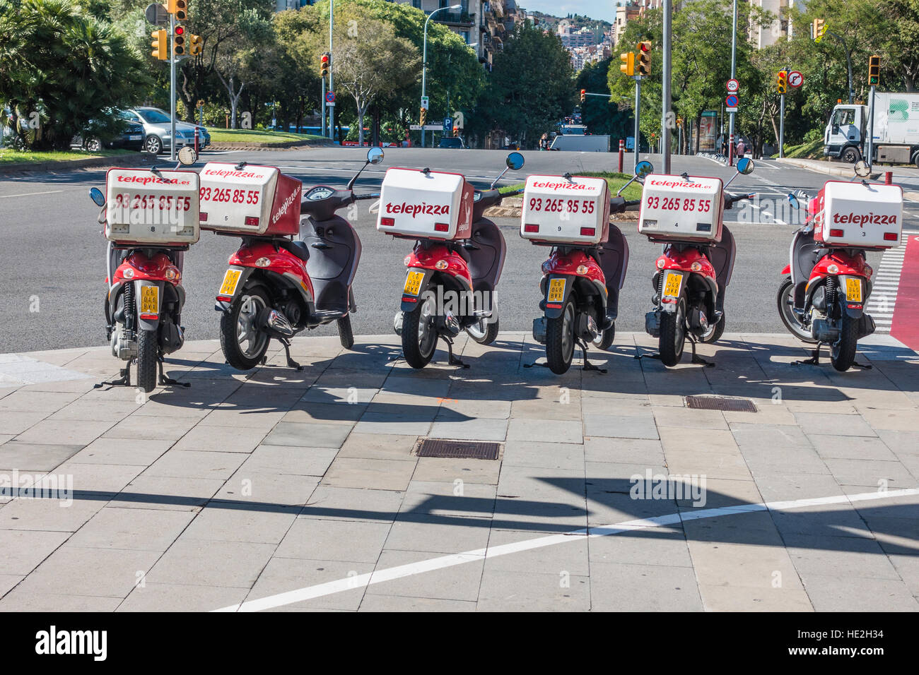 Eine Reihe von Telepizza Motoscooters geparkt auf einem Bürgersteig in Barcelona, Spanien mit ihrer Lieferung-Boxen auf dem Rücken befestigt. Stockfoto
