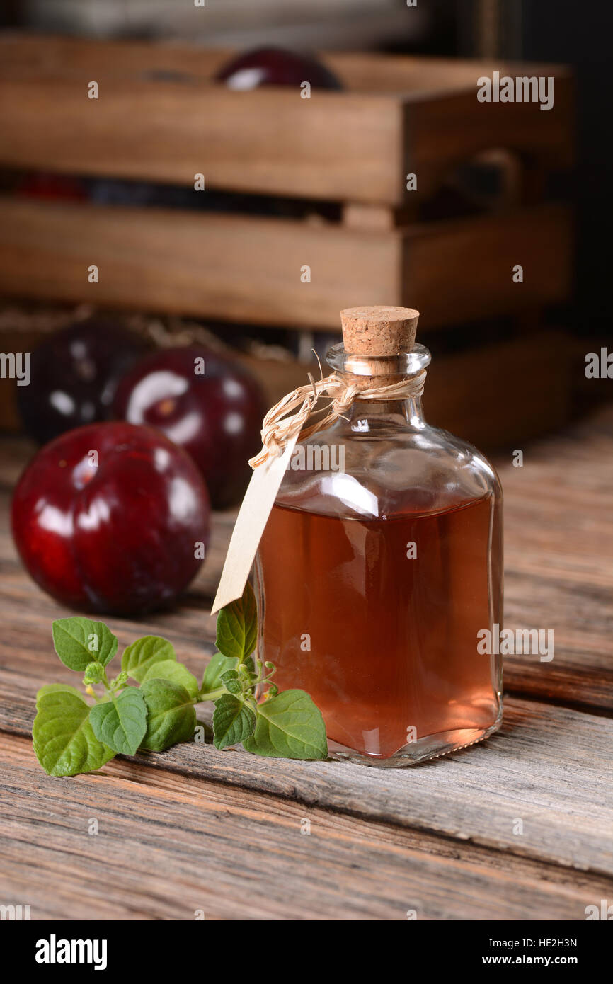 Pflaumensaft in kleine Glasflasche mit Früchten um Stockfoto