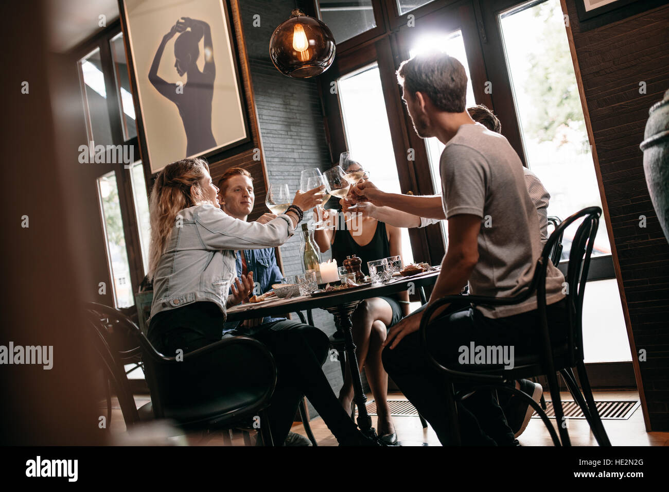 Gruppe von Freunden Toasten Wein im Restaurant. Junger Mann und Frau am Tisch sitzen und Getränke im Café toasten. Stockfoto