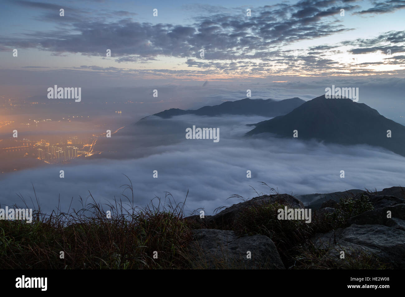 Wolken überrollen Berggipfel auf Lantau Island, gesehen vom Lantau Peak (der 2. höchste Berg in Hongkong, China) in der Morgendämmerung. Stockfoto
