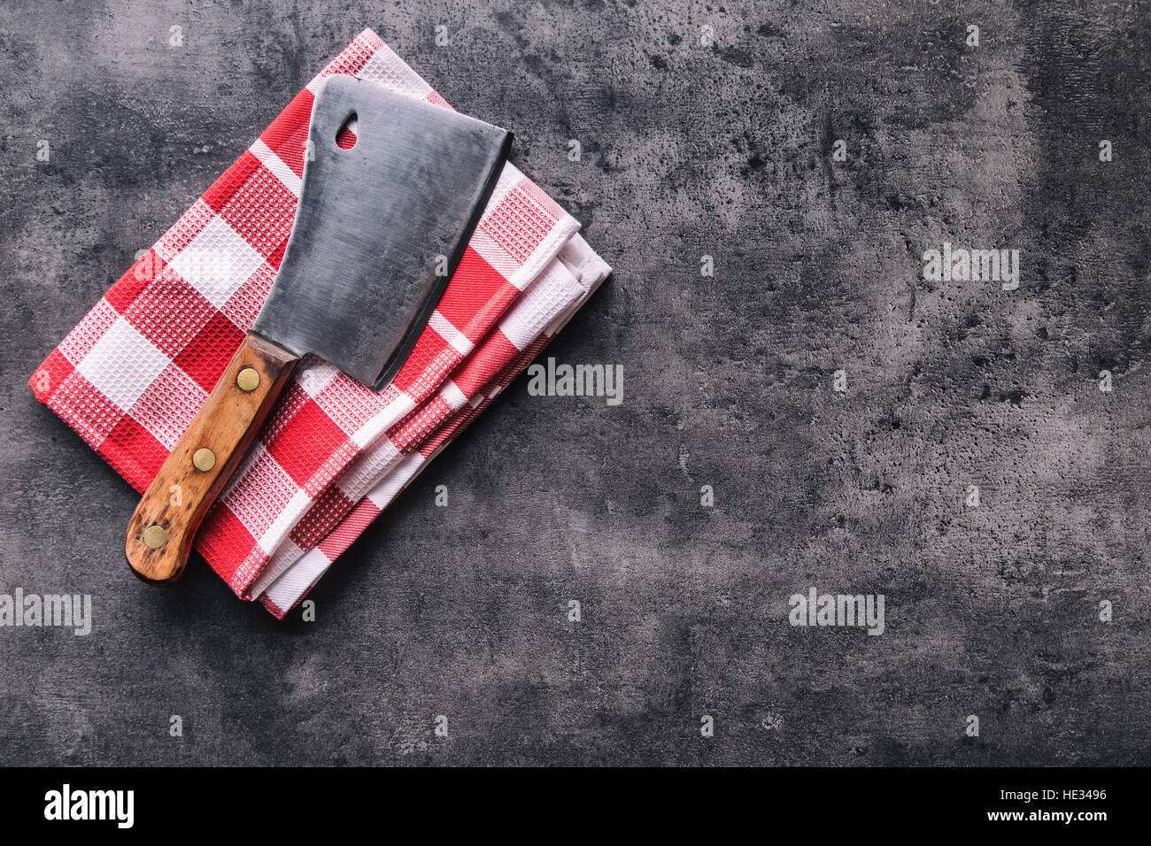 Metzger. Vintage Metzger Fleischerbeile mit Tuch Handtuch auf dunklen Beton oder Holz Küche Board. Stockfoto