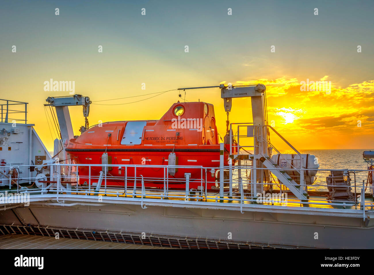 Orange Rettungsboot auf den Frachter am Meer bei Sonnenuntergang Stockfoto