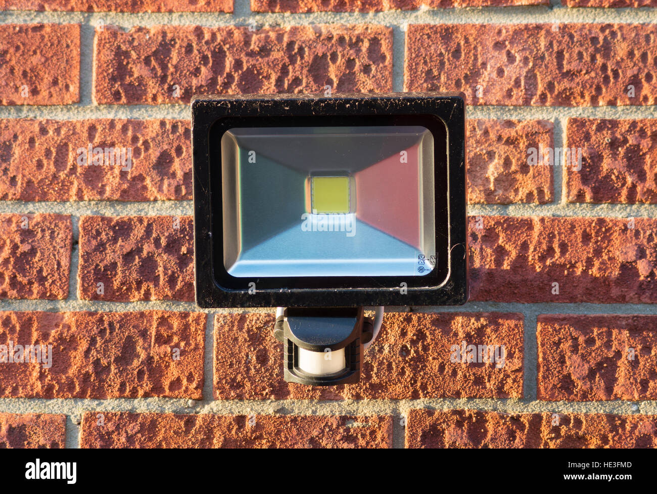 LED-Sicherheit-Strahler mit integraler PIR-Bewegungsmelder, die auf eine äußere Mauer montiert. England, UK. Stockfoto