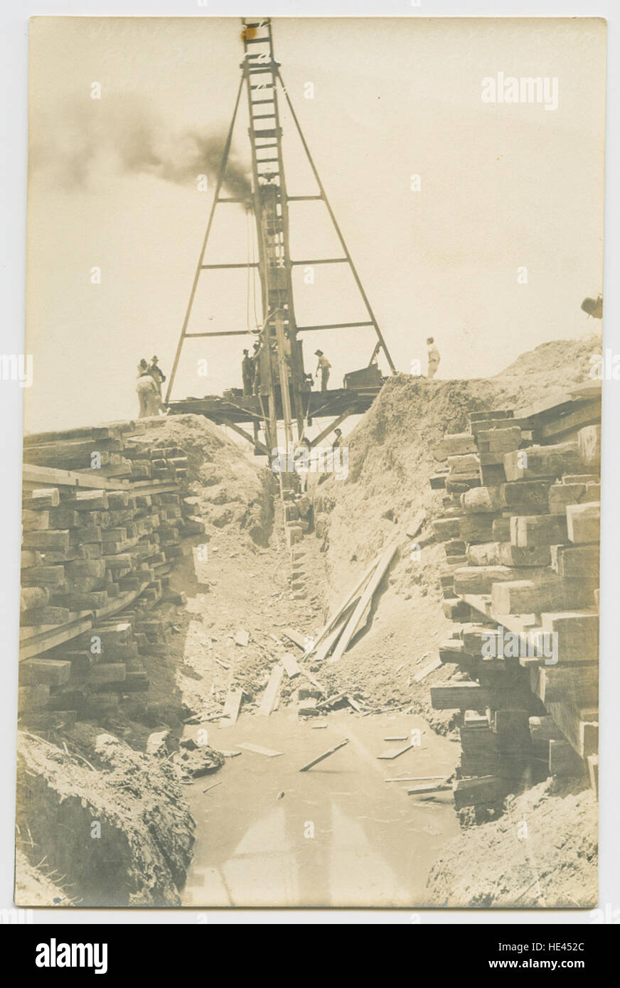 Das Bild zeigt Bauarbeiten am White Rock Creek Reservoir Dam in Texas. Es zeigt die Verwendung eines Pfahltreibers über den Bach als Teil des Dammbaus. Die historische Szene zeigt die technischen Techniken des frühen 20. Jahrhunderts, die zur Schaffung des White Rock Lake Reservoir verwendet wurden. Stockfoto
