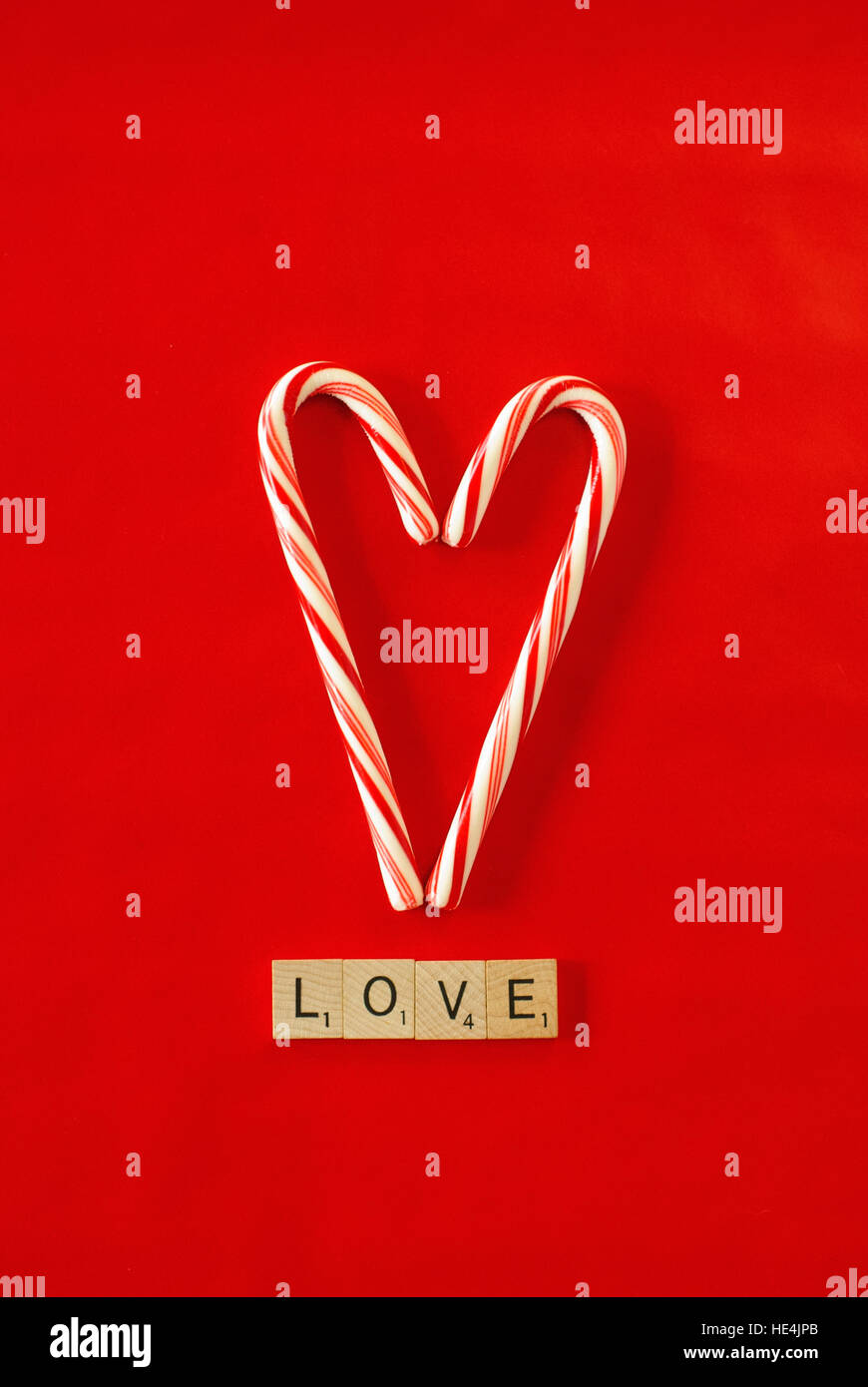 Candy Cane Herz auf rotem Grund, Liebe in Scrabble-Buchstaben Stockfoto