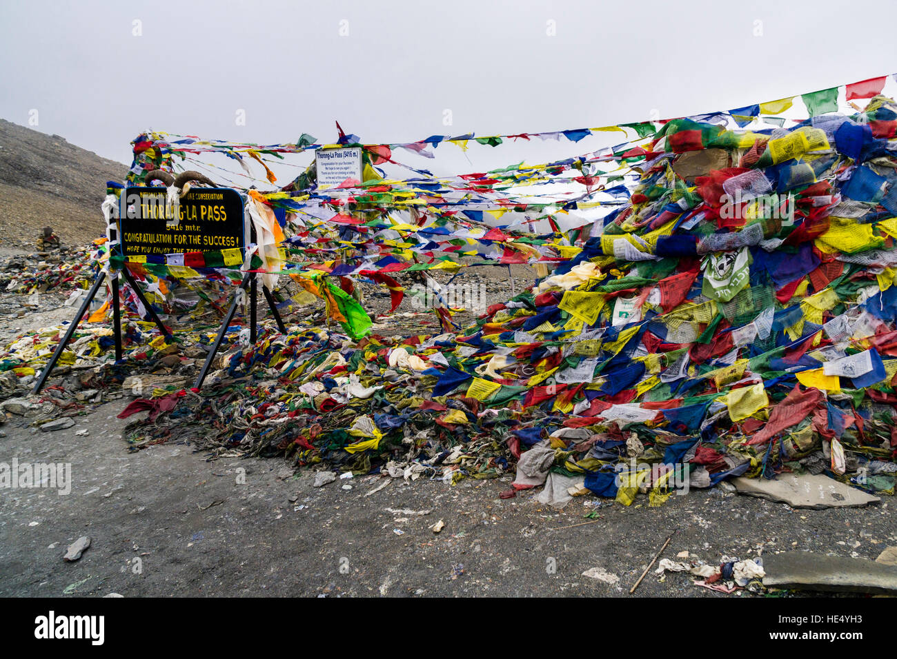 Tibetische Gebetsfahnen sind um einen Haufen von Steinen und der Wegweiser auf thorong La gewickelt, 5416 Meter über dem Meeresspiegel, dem Pass zwischen dem oberen marsy Stockfoto