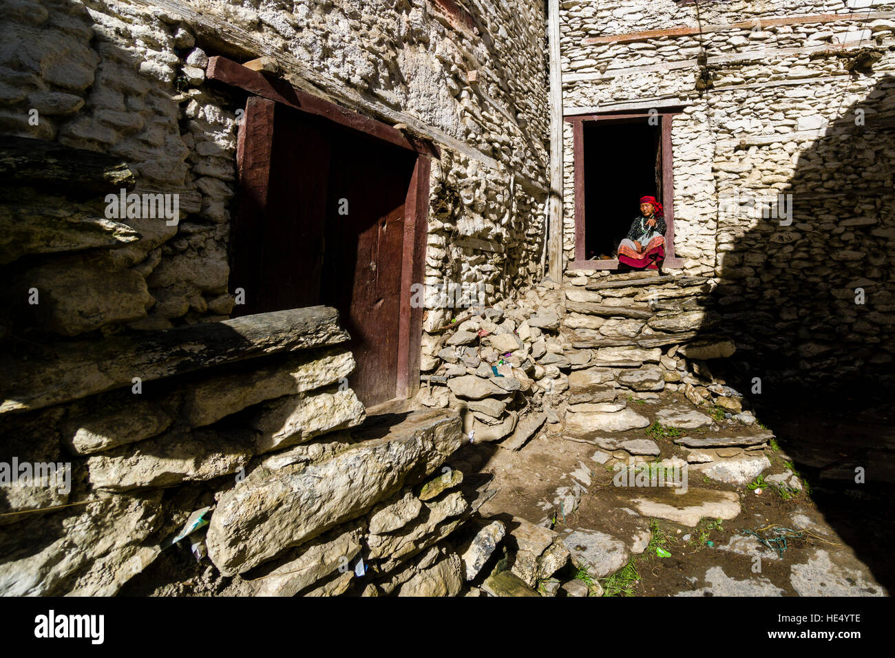 Eine alte lokale Landwirte Frau sitzt in der Tür eines Hauses aus Stein Stockfoto