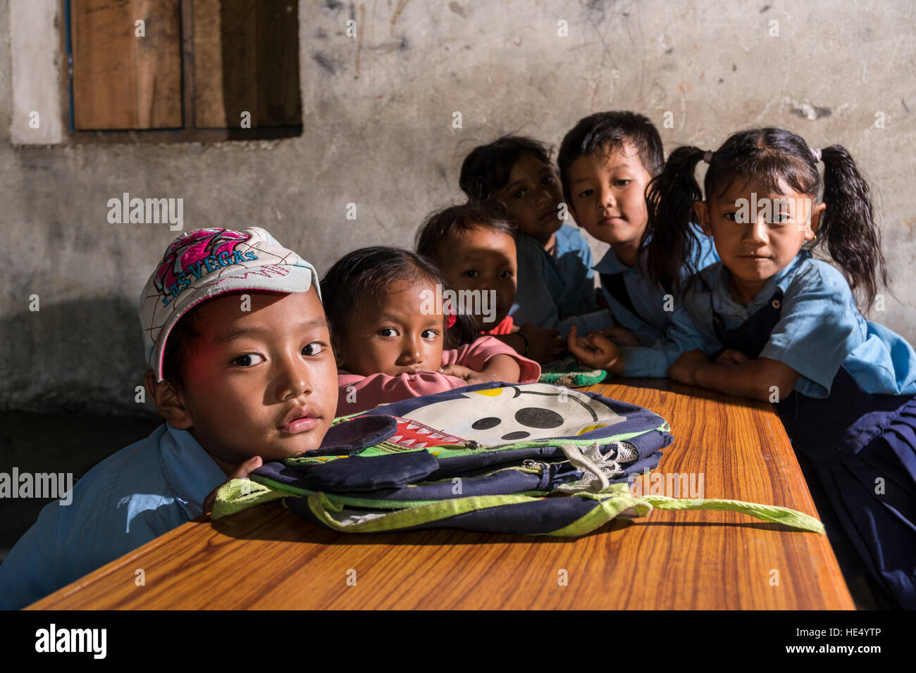 Eine Gruppe von Kindern in blaue Kleider sitzt an einem Tisch in der örtlichen Schule Stockfoto