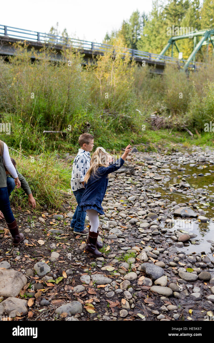 Geschwister werfen Felsen im Fluss McKenzie zusammen in der Lifestyle-Aufnahme der Kinder mit Spaß zu spielen. Stockfoto