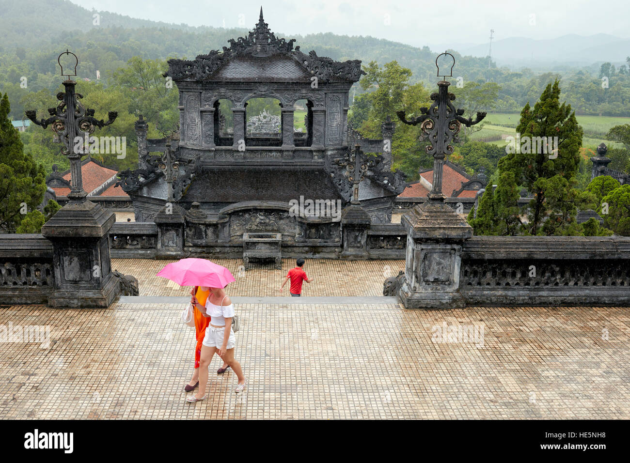 Touristen, die im Regen auf einer Terrasse am Saluation Court des Grabes von Khai Dinh (Ung Grab) spazieren. Hue, Vietnam. Stockfoto