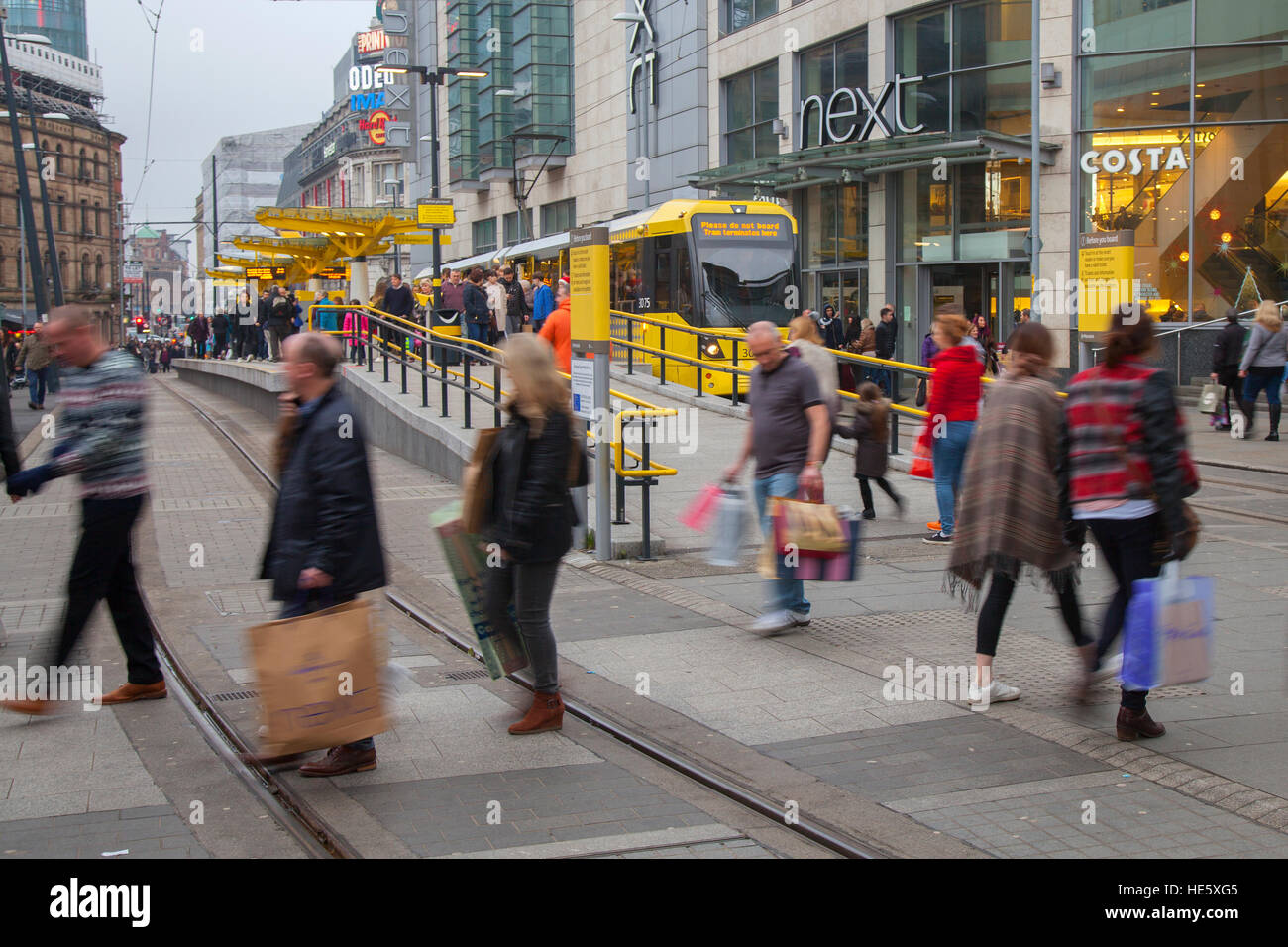 Alltägliche Lifestyle Street Centre Szenen in Manchester, Großbritannien. Dezember 2016. Der Verkauf vor dem Boxing Day beginnt in der Stadt. Mehrere Einzelhändler werben jetzt für Rabatte in der letzten Einkaufswoche vor Weihnachten. Käufer, Käufer mit einer Tasche voller Einkäufe und in einigen Fällen viele, viele Waren, die von einer großen Auswahl an speziellen High-Class-Einzelhändlern in und um Piccadilly City Centre Tramway gekauft wurden. Stockfoto