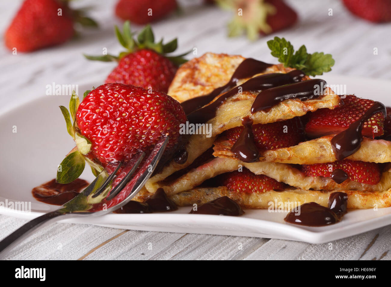 Crepes mit frischen Erdbeeren und Schokolade Topping Makro auf einem Teller. horizontale Stockfoto