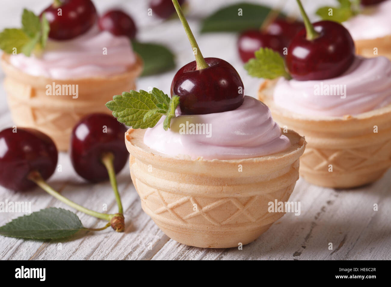 Mini-Törtchen mit rosa Sahne und frischen Kirschen. Closeup horizontale Stockfoto