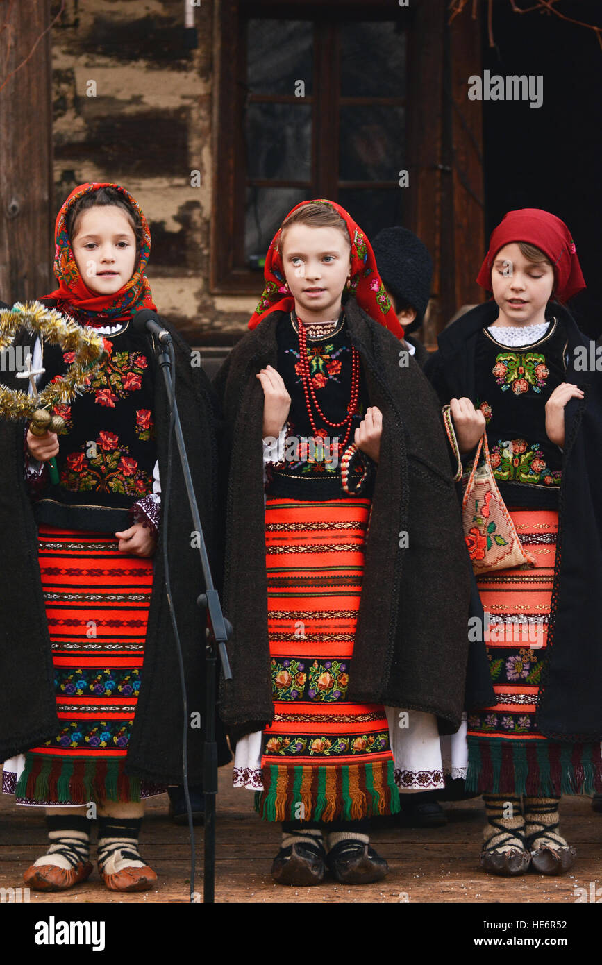 Rumänische Kinder Kleid in traditionellen Kostümen, die auf einen lokalen Weihnachtsmarkt singen Weihnachtslieder Stockfoto
