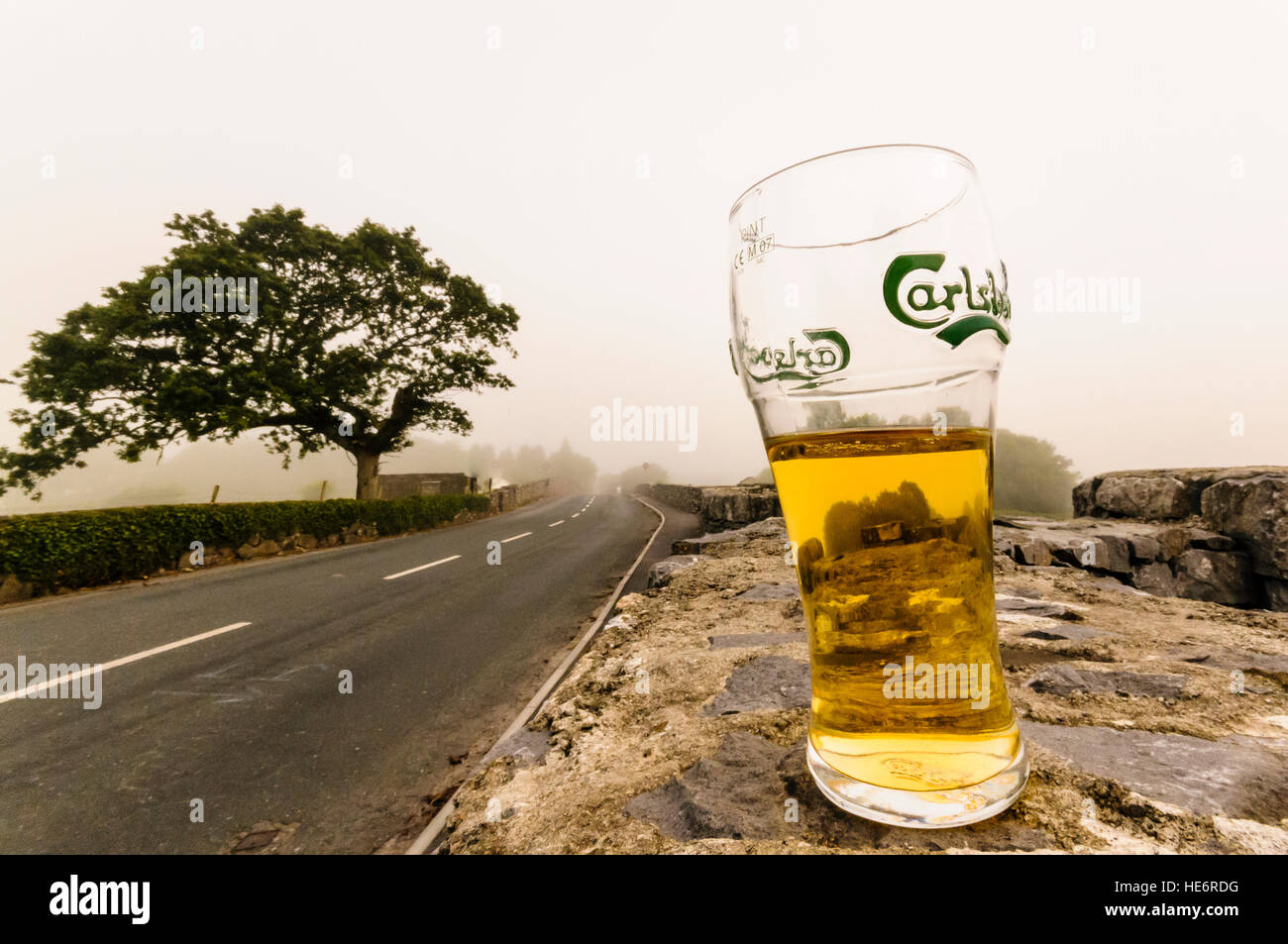 Ein halb fertig Pint Carlsberg Lagerbier bleibt auf einer Steinmauer im ländlichen Irland an einem Sonntagmorgen. Stockfoto