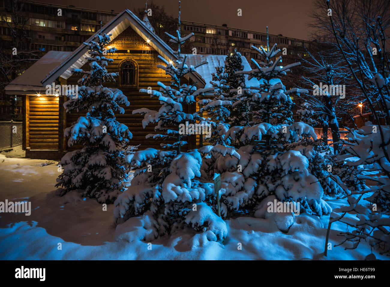 kleine Hütte und Sträucher mit Schnee bedeckt, auf dem Hintergrund des Hochhauses in der Nacht Stockfoto