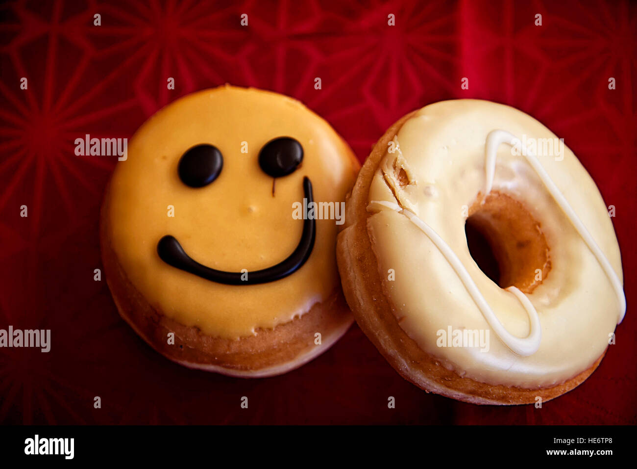 Smiley-Gesicht-Donut und vereisten Donut auf roten Tischdecke Stockfoto