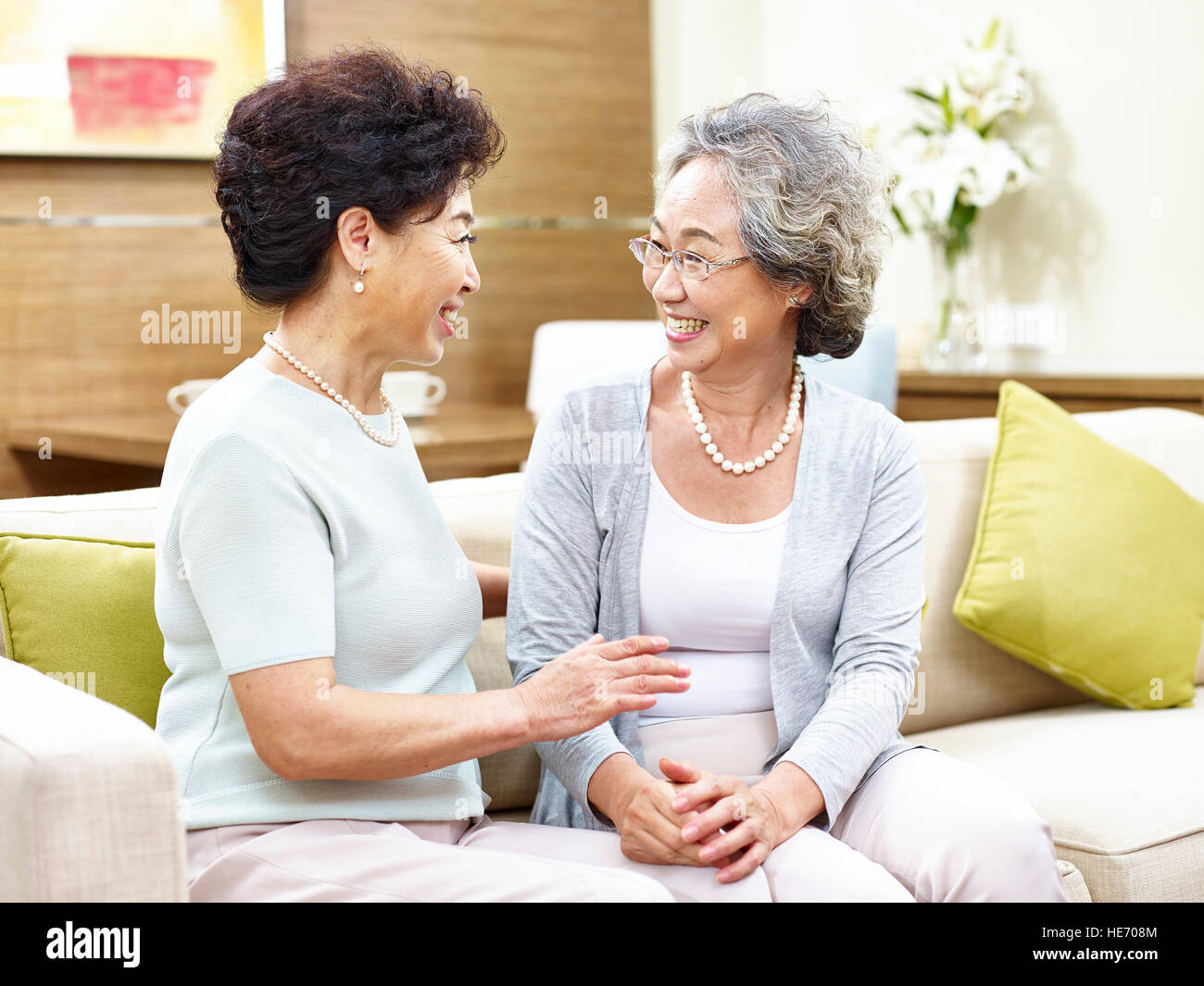 zwei asiatische senior Frau sitzt auf dem Sofa im Chat, glücklich und lächelnd. Stockfoto