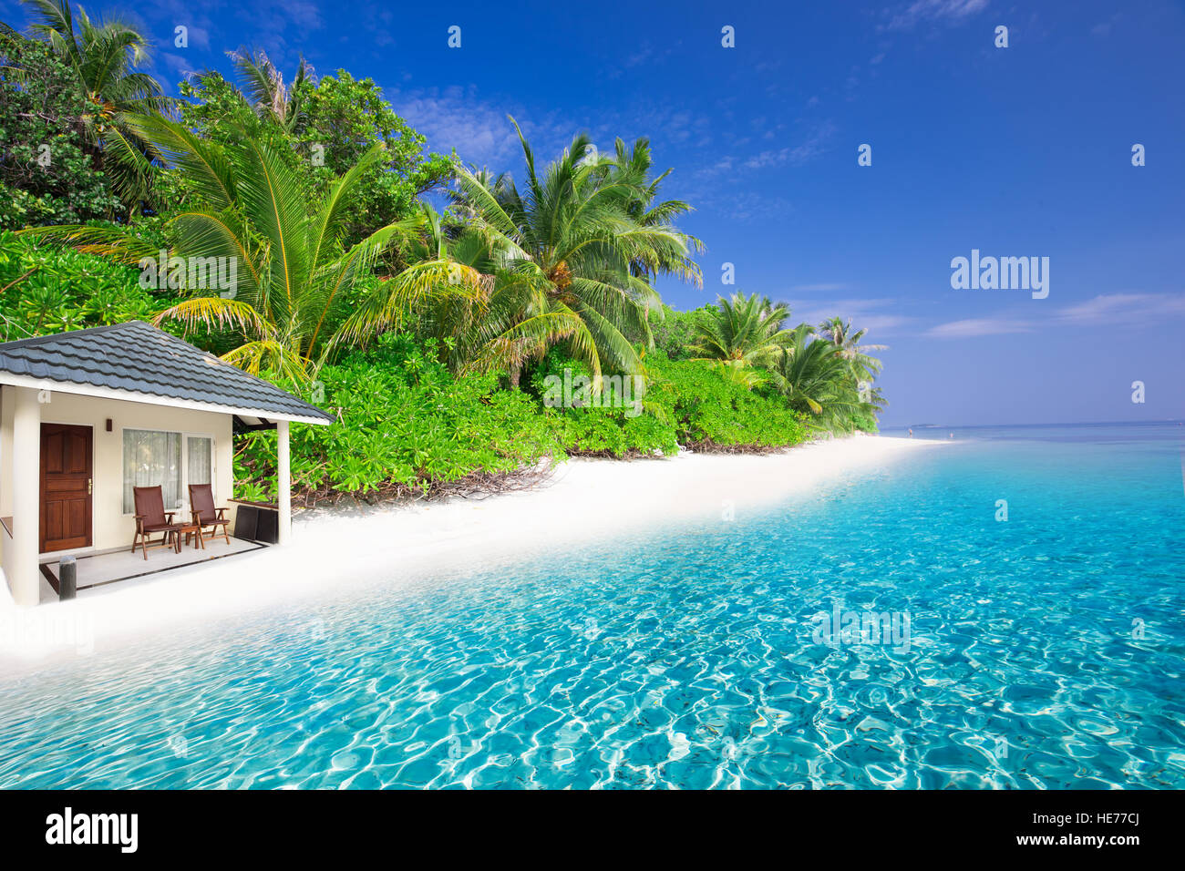 Overwater Bungalows auf tropischen Insel mit Sandstrand, Palmen und türkisfarbenem klarem Wasser Stockfoto