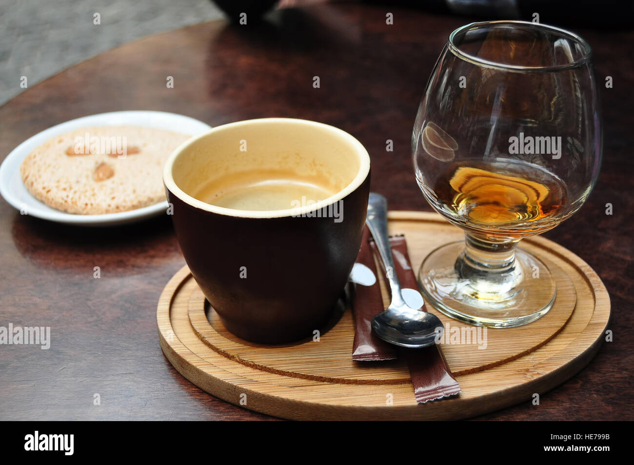 Dunkle Keramik Tasse Kaffee, Glas Cognac und italienischer Mandel-Cantuccini Cookie auf einem weißen Teller auf einem alten Holztisch im café Stockfoto