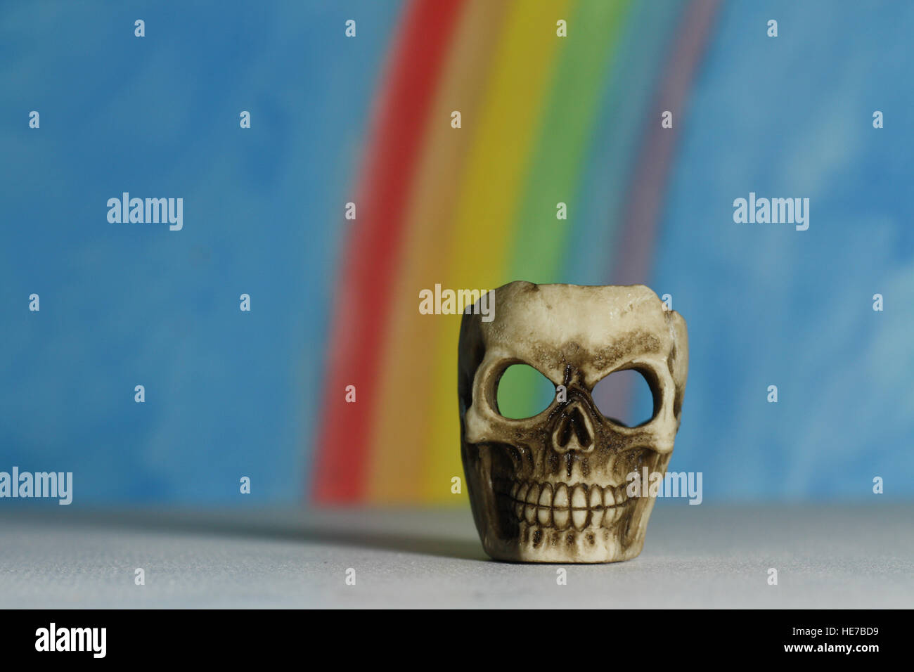 Menschlicher Schädel mit blauem Himmel und Regenbogen Hintergrund, ein Symbol des Todes, Vanitas, Horror und Yorick in Shakespeares Hamlet. Stockfoto