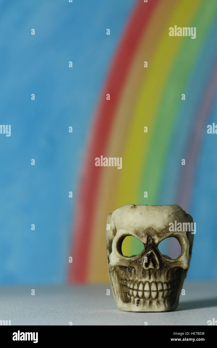 Menschlicher Schädel mit blauem Himmel und Regenbogen Hintergrund, ein Symbol des Todes, Vanitas, Horror und Yorick in Shakespeares Hamlet. Stockfoto