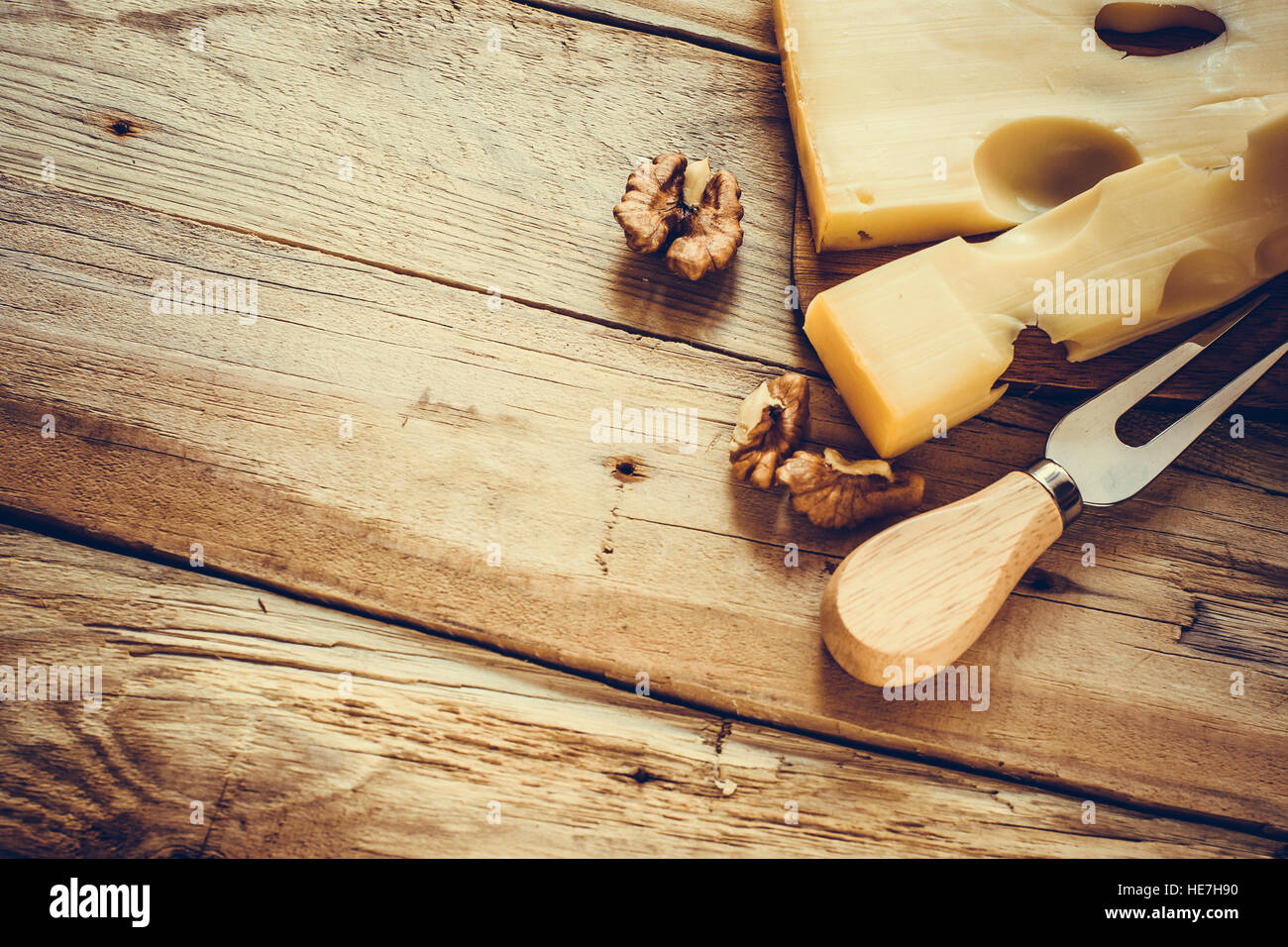 Maasdam Käse mit Walnüssen auf eine dunkle Board oben rechts Schnittwinkel mit Käse Gabel, Tiefenschärfe, oben flach, Holztisch Stockfoto