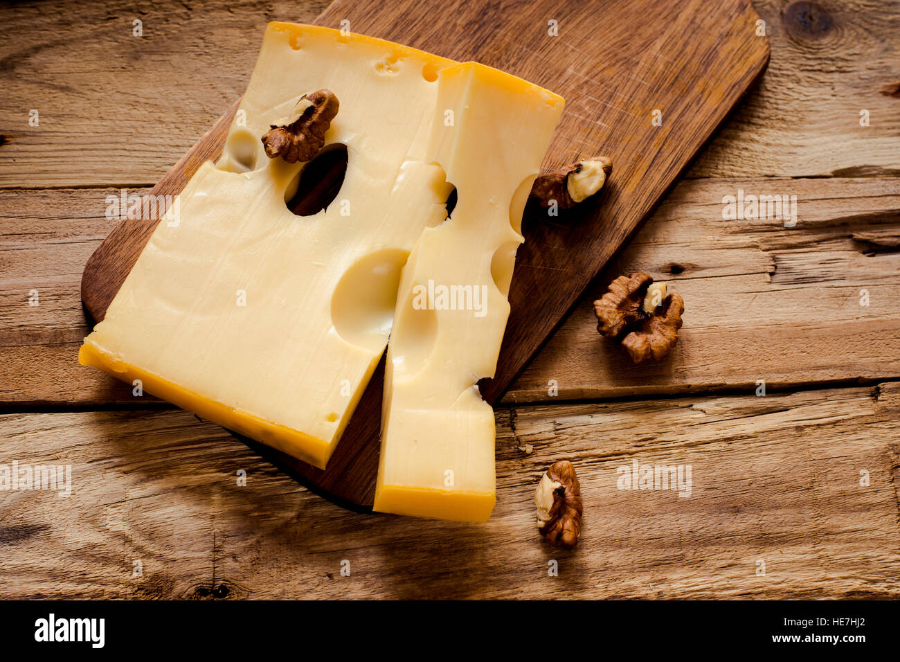 Cavernosus Maasdam Käse auf einem dunklen Schneidebrett mit Nüssen Draufsicht, selektiven Fokus Stockfoto