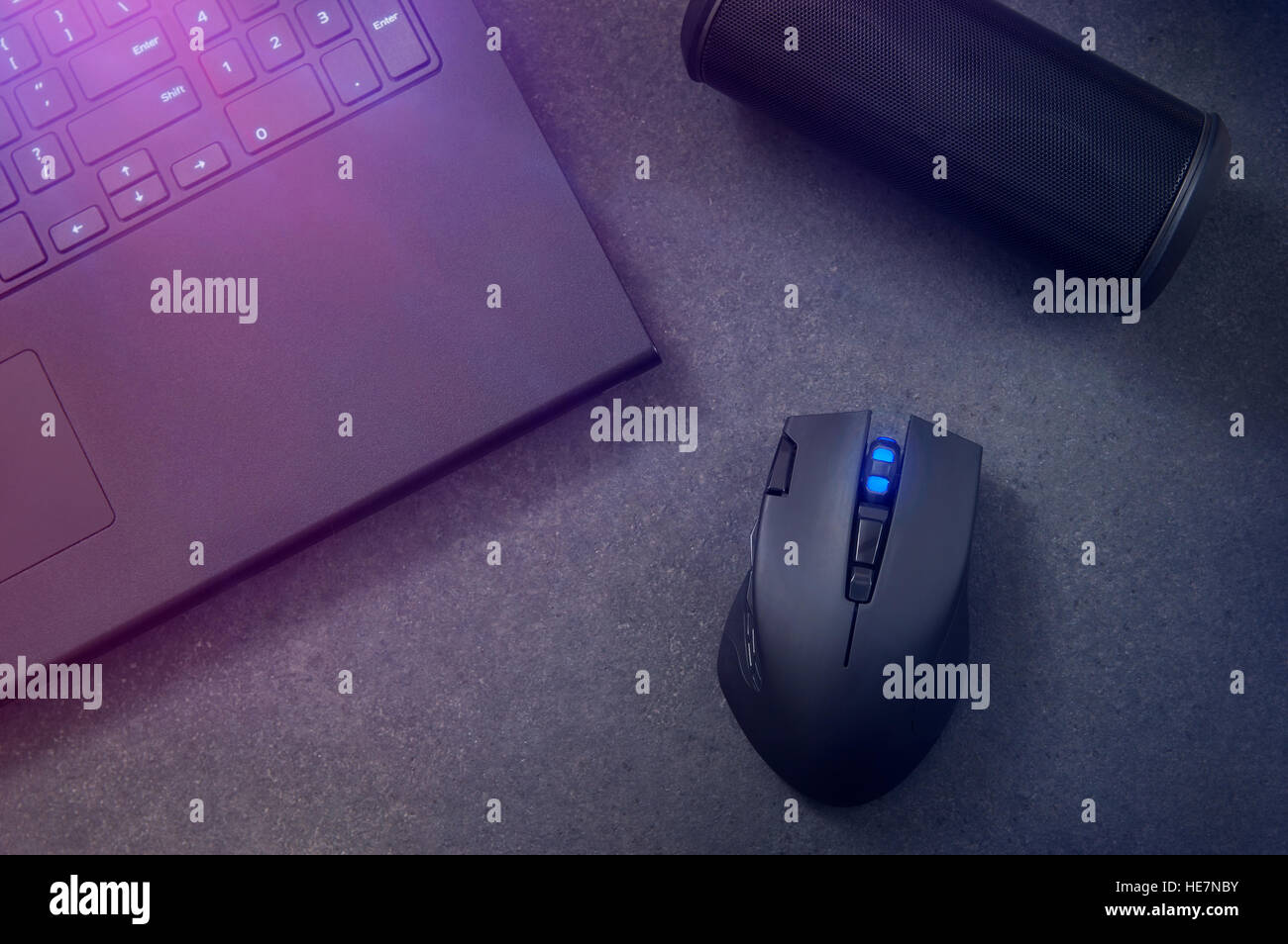 Gaming-Maus, tragbare Lautsprecher und Laptop in der Nacht. Stockfoto