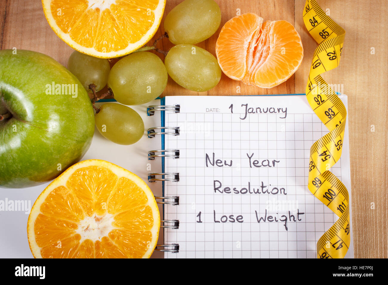 New Years Resolutionen abnehmen geschrieben in Notebook und frisches Obst mit Maßband, Konzept der gesunden Lebensweise Stockfoto