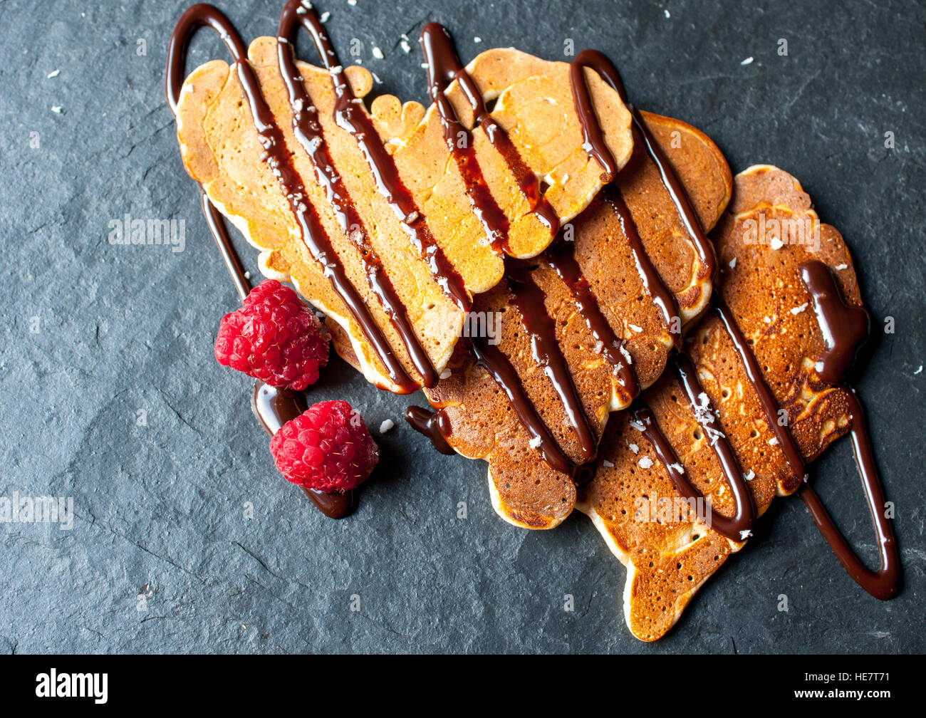 Pfannkuchen in die Form eines Herzens mit Schokolade Sirup und Himbeeren am Valentinstag. Stockfoto