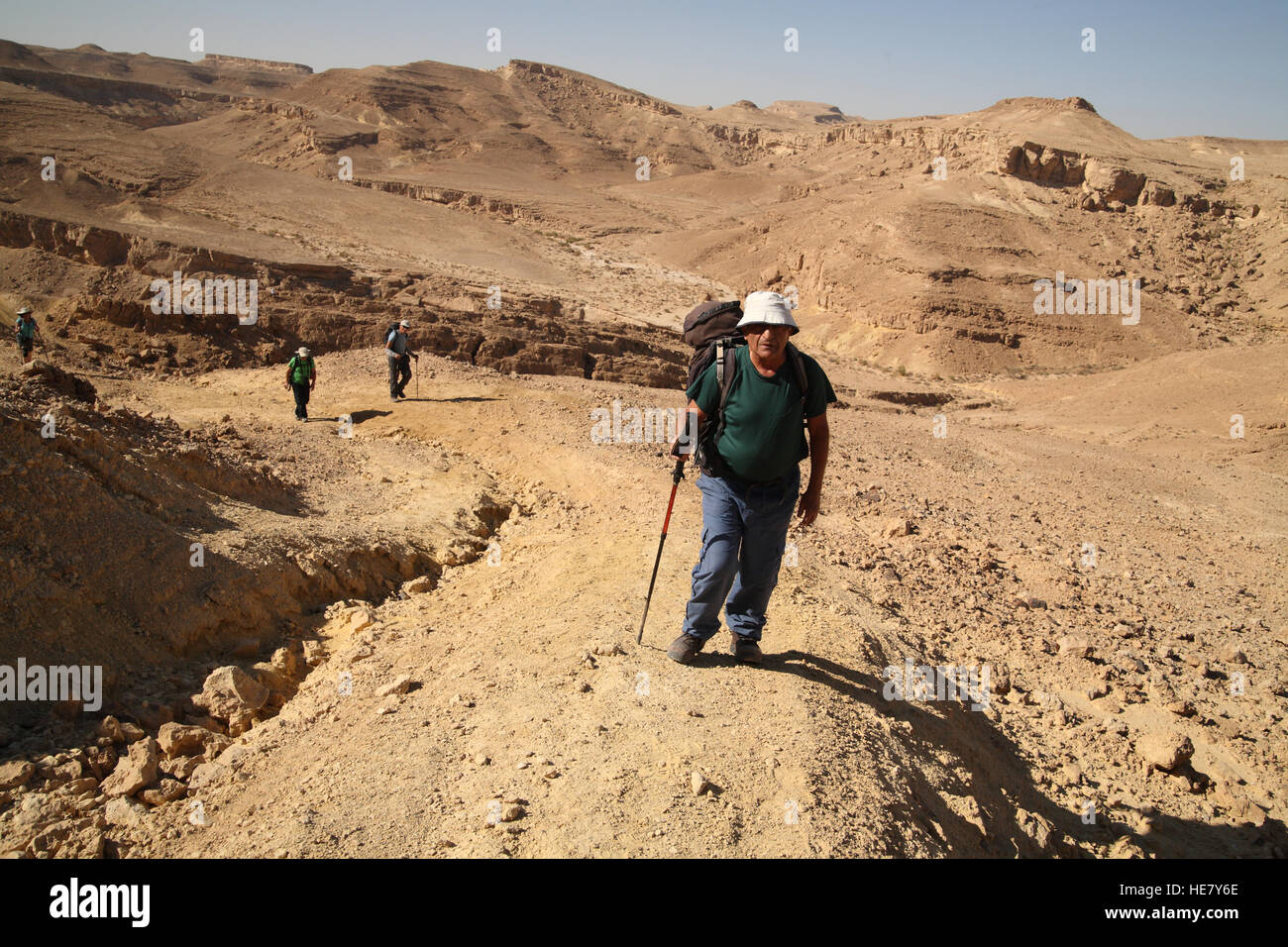 Eine 79 Jahre alte Senioren Mann Wanderer führt andere Wanderer zu Fuß hinauf über Nachal oder Nahal Marzeva in der Wüste Negev, Israel. Stockfoto