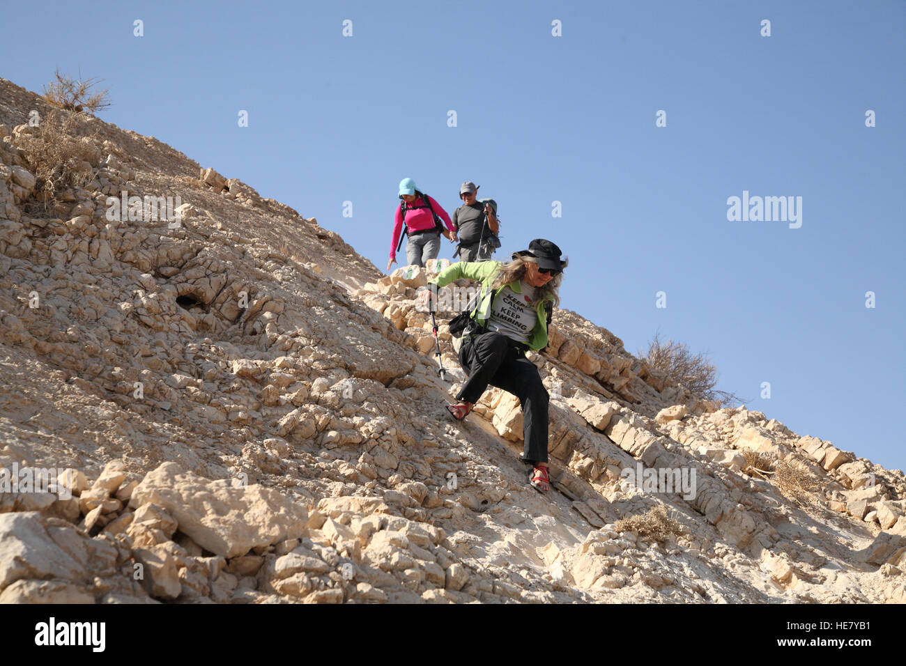 Eine ältere Wanderin steigt vorsichtig einen sehr steilen Felshang vom Mount Massor mit einem Wanderstock ab, um die Negev-Wüste zu vermeiden. Stockfoto