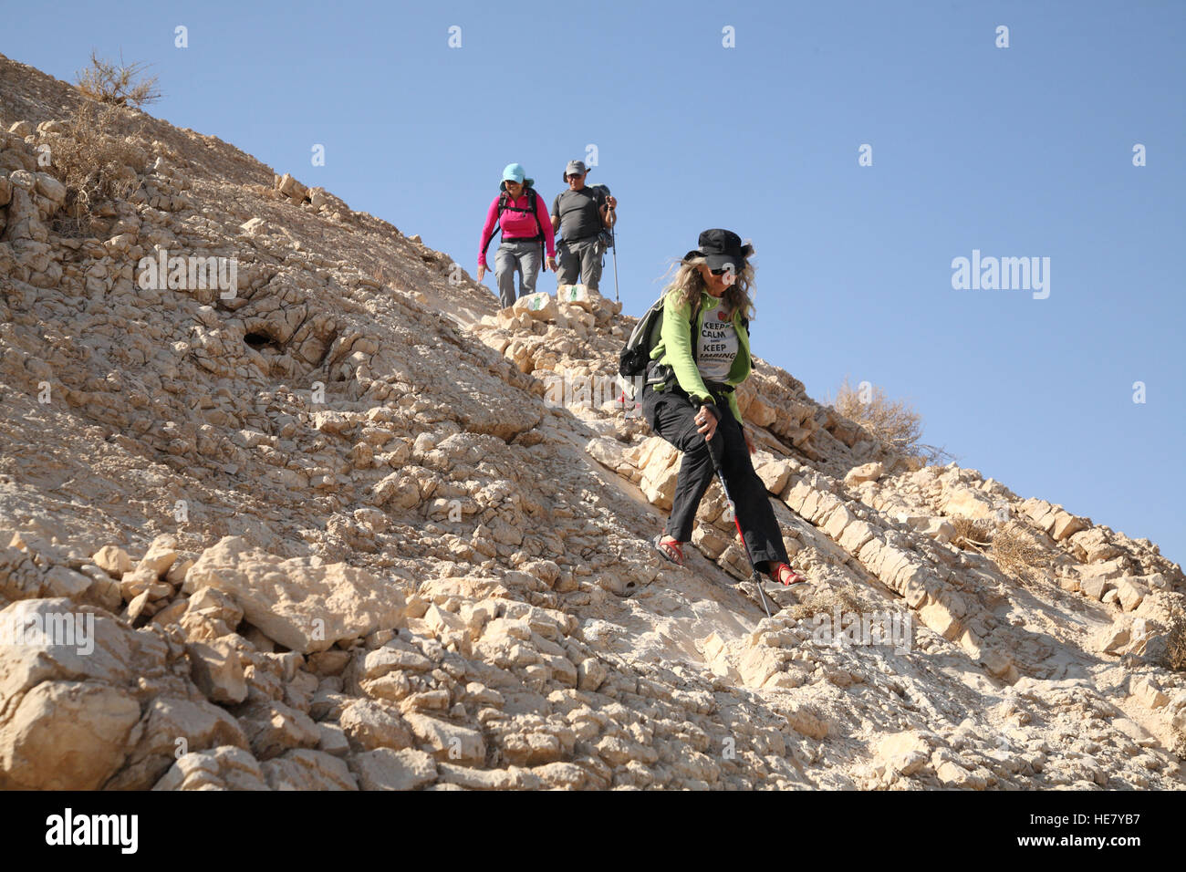 Eine Seniorin Frau Wanderer entstammt sorgfältig einen sehr steilen felsigen Hang Mount Massor mit einem Wanderstock, fallen zu vermeiden Stockfoto