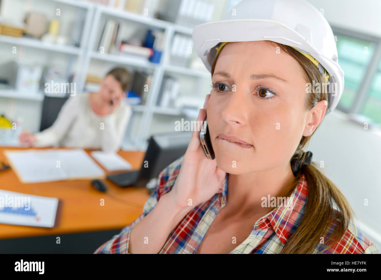 Lady Bauarbeiterhelm, am Handy Lippe beißen zu tragen Stockfoto