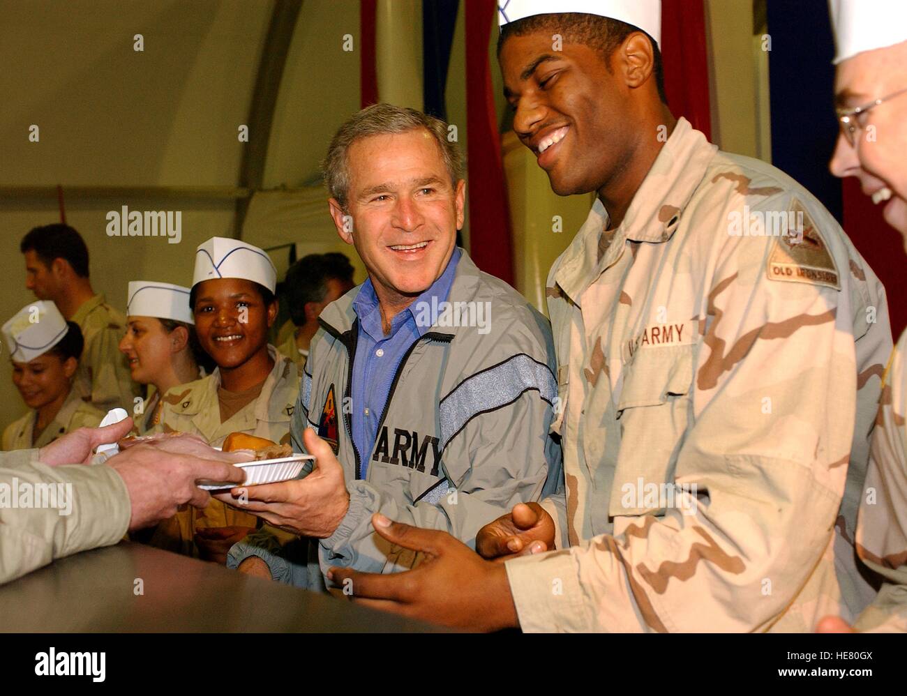 US-Präsident George W. Bush hilft US-Soldaten dienen eine traditionelle Thanksgiving Festessen an der Bagdad International Airport Bob Hope Dining Facility 27. November 2003 in Bagdad, Irak. Stockfoto