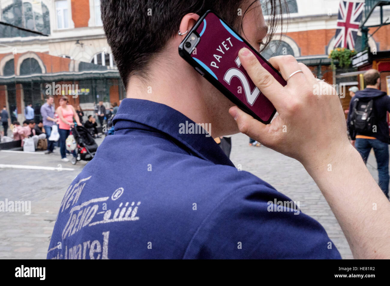 Ein junger Fan von West Ham United macht einen Anruf von seinem Smartphone. Das Telefon verfügt über eine Schutzhülle, die mit dem Namen Payet und 27 Stockfoto
