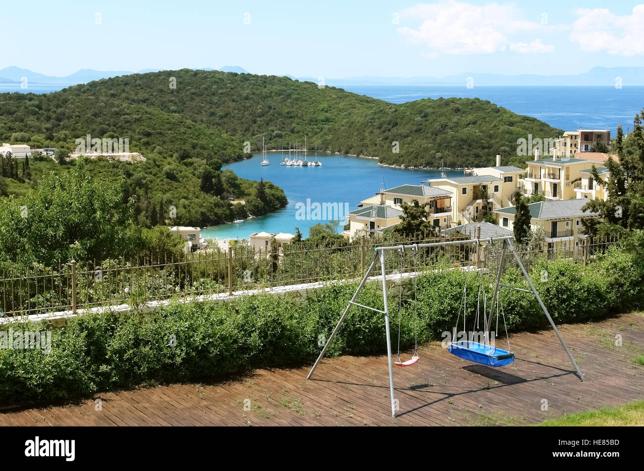 Schaukel und ein Blick auf die blaue Bucht mit grünen Bergen und Yachten im Ionischen Meer in Griechenland. Stockfoto