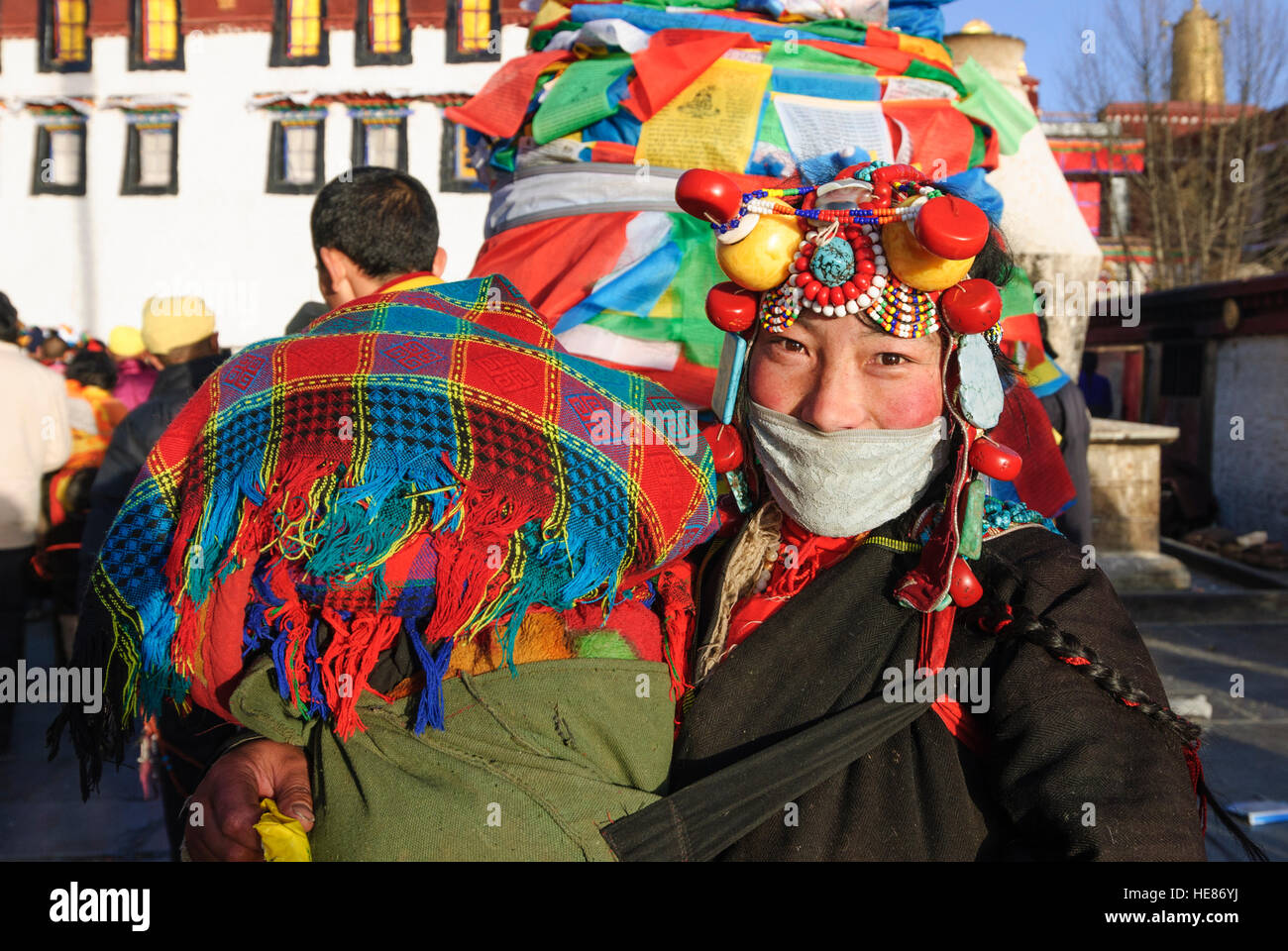 Lhasa: Jokhang-Tempel; Tibetische Frau mit Kind, Türkis Kopfschmuck, Korallen, Bernstein und Perlen, getragen auf Festivals, Tibet, China Stockfoto