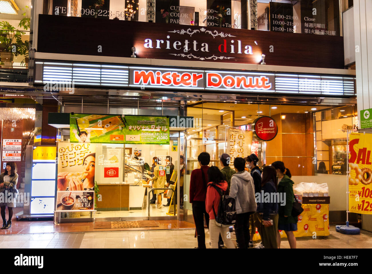 Japan, Kumamoto, Shimotori Arcade Street. Mister Donut Restaurant mit der jungen Menschen über zu gehen. Nacht. Stockfoto