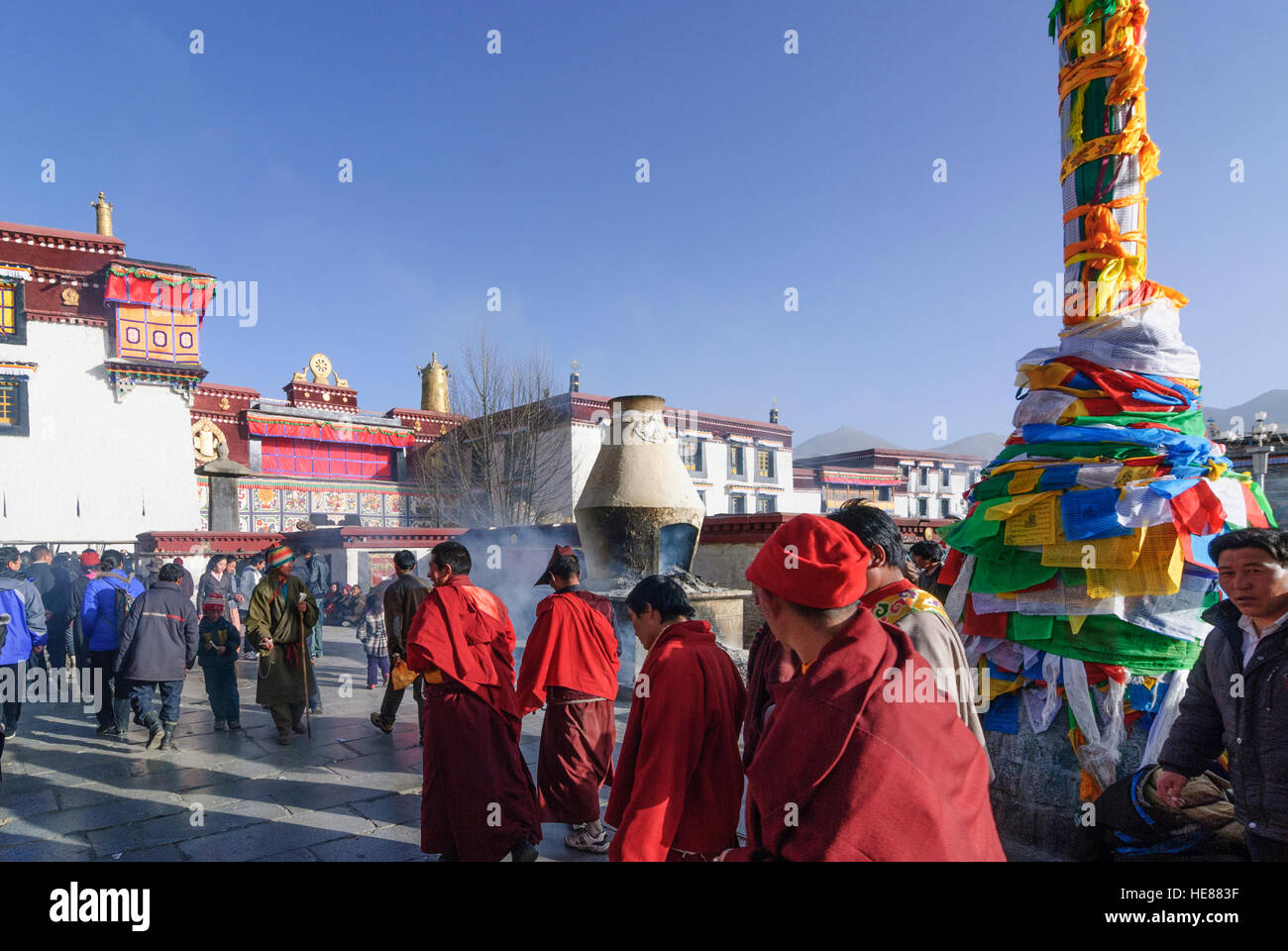 Lhasa: Tibeter umrunden die Barkhor (Pilgerweg) ein Darchen (Flagpost) vor dem Jokhang-Tempel, Tibet, China Stockfoto