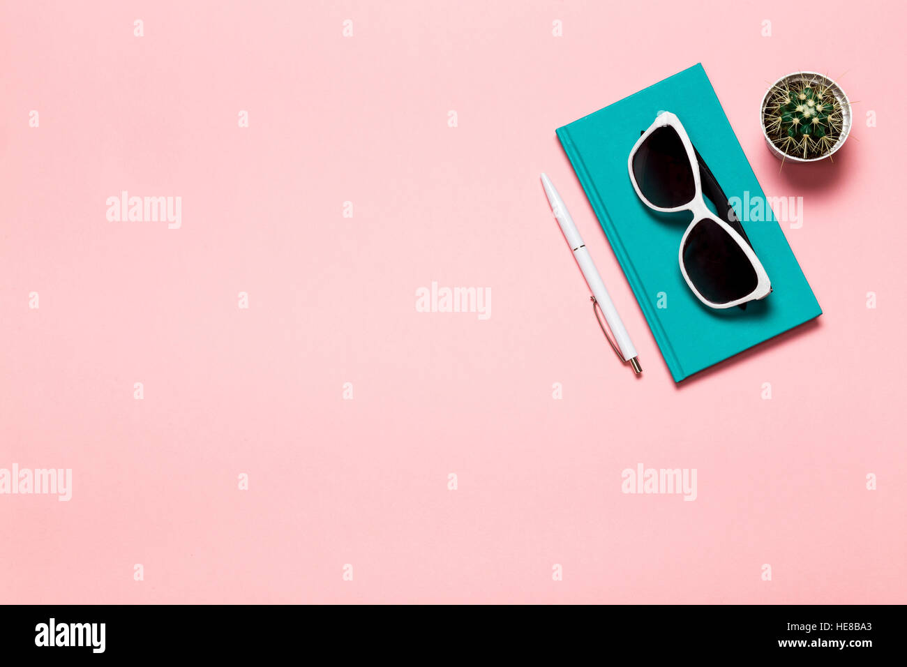 Kreative flach legen Foto des Arbeitsbereichs Schreibtisch mit Aquamarin Notebook, Brillen, Kaktus mit Kopie Raum rosa Hintergrund, minimalistischen Stil Stockfoto