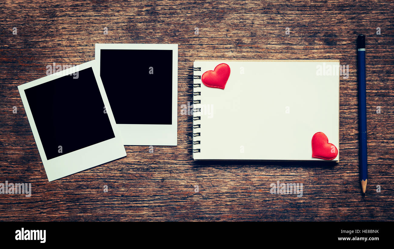 Leere Foto Frame, Notebook, Bleistift und roten Herz auf Holztisch Hintergrund. Stockfoto