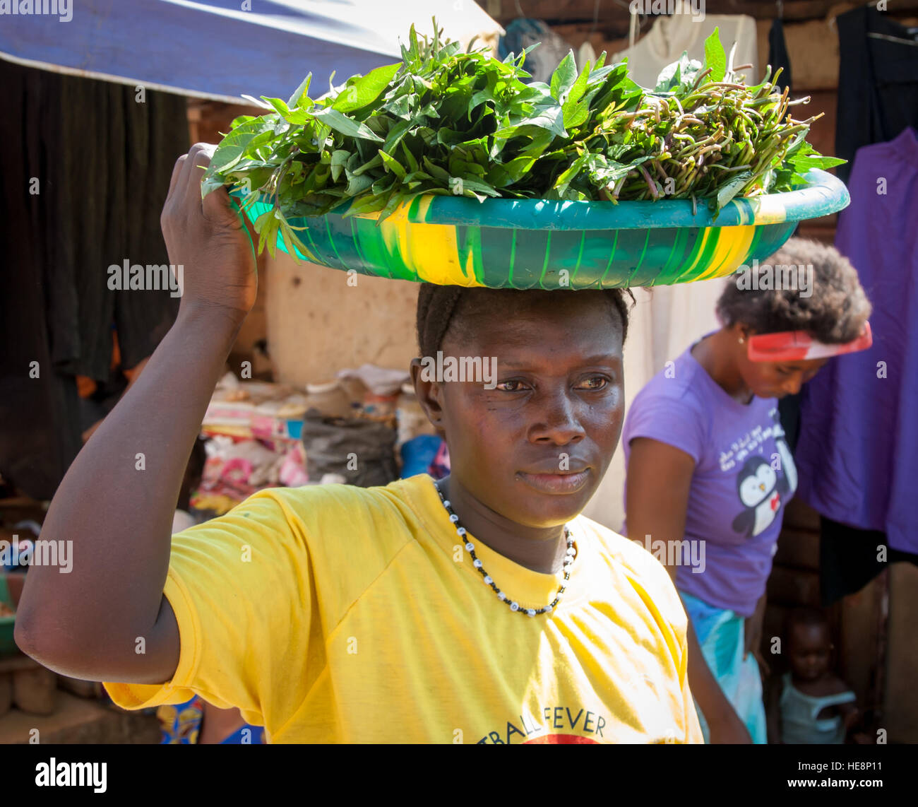 Auch in Sierra Leone sind Kartoffelblätter ein wichtiges Nahrungsmittel. Diese Frau bringt ihren Kauf mit nach Hause Stockfoto