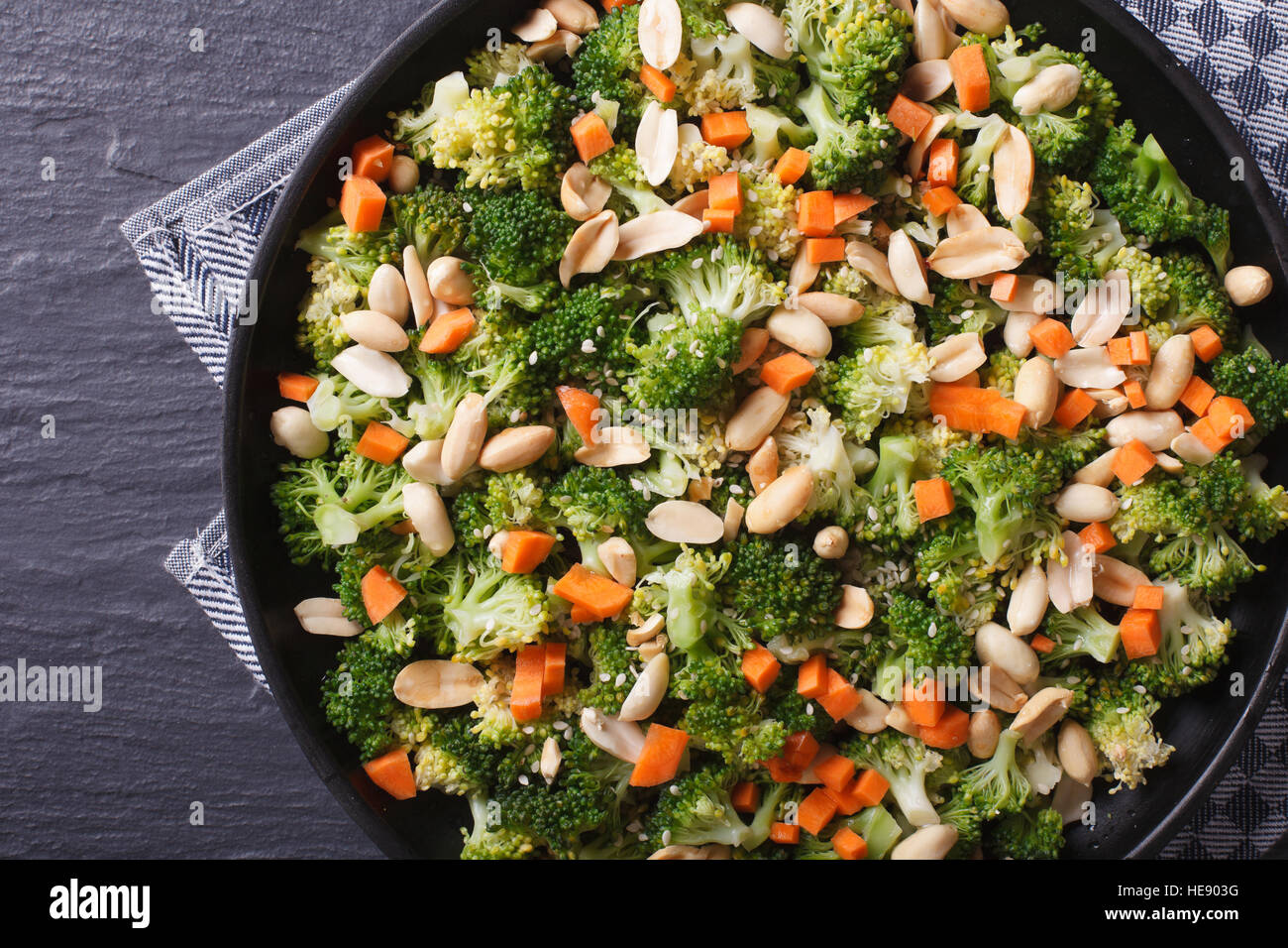 Gesunde Ernährung: Brokkoli mit Erdnüssen und Karotten Nahaufnahme auf einer schwarzen Platte. horizontale Ansicht von oben Stockfoto