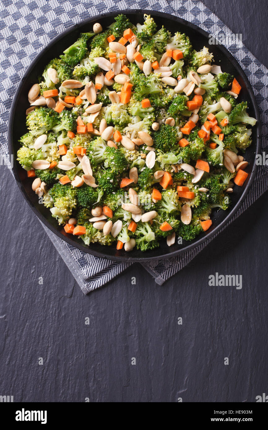 Brokkoli mit Erdnüssen und Karotten eine schwarze Platte. Vertikale Ansicht von oben Stockfoto