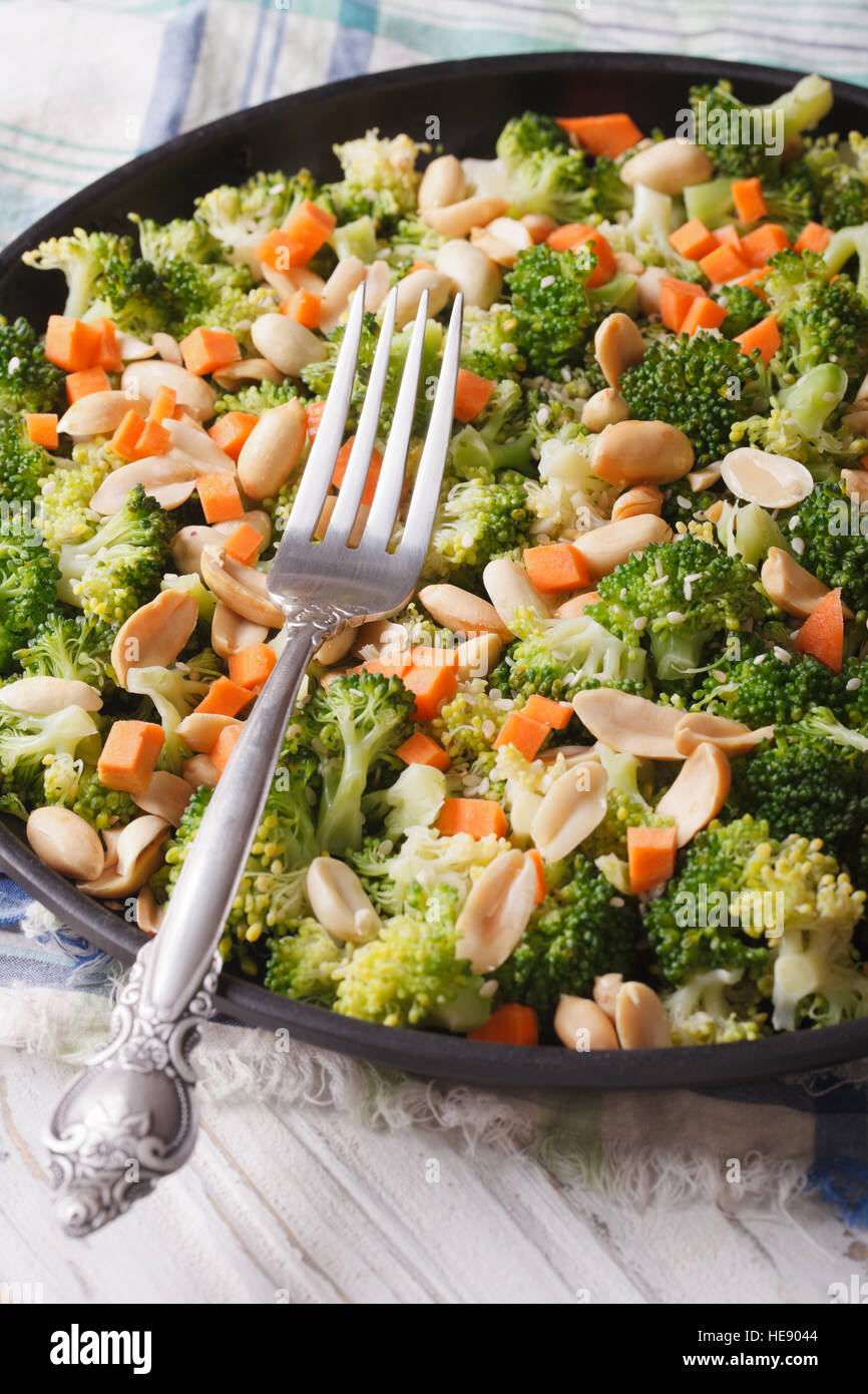 Diätetische Salat mit Brokkoli, Karotten und Erdnüssen Nahaufnahme auf einer Platte. vertikale Stockfoto